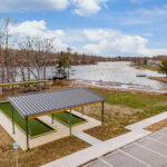 Aerial view of the completed Fairfield Glade bocce ball court with standing seam sunshade roofs beside the lake