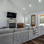 Whitewashed brick fireplace with mounted TV in the vaulted great room