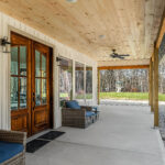 Wraparound covered porch with a pine tongue-and-groove ceiling, ceiling fans, and wicker seating