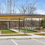 Front view of the completed bocce ball court with standing seam roof, structural steel columns, and green turf lanes trimmed in yellow