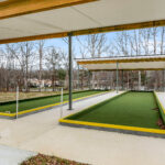 View from beneath the sunshade structure showing the structural steel columns, Glu-Lam beam, and turf bocce lanes