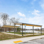View of the bocce ball court shelters from the parking area, with accessible parking signage and the lake behind
