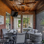 Interior view of the outdoor living space with stained tongue-and-groove ceiling, ceiling fans, TV, and The Powers' 19th Hole sign
