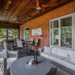 Full interior view of the outdoor living space with hot tub, dining area, sofa seating, and the golf course visible through the windows