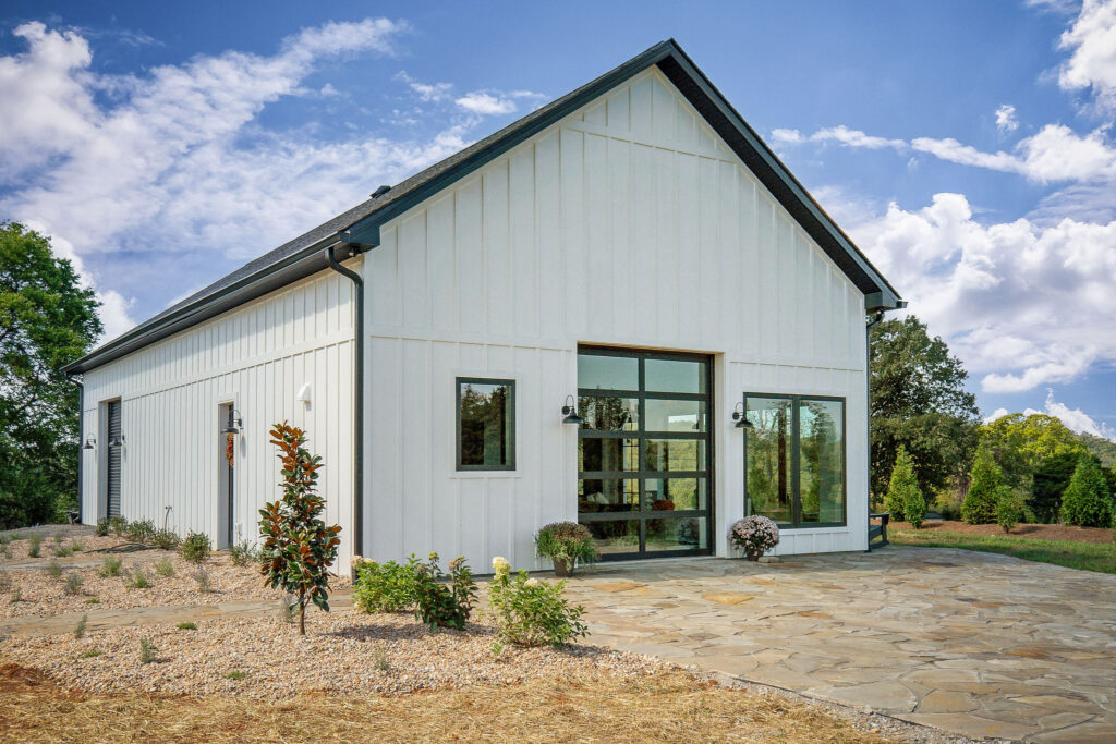 Side view of a custom white board-and-batten guest home by East Tennessee Contractors, with a black roll-up garage door