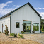 Side view of a custom white board-and-batten guest home by East Tennessee Contractors, with a black roll-up garage door