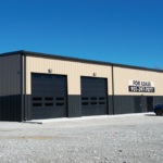 Completed metal building with two-tone tan and black exterior and overhead doors in Crossville, TN