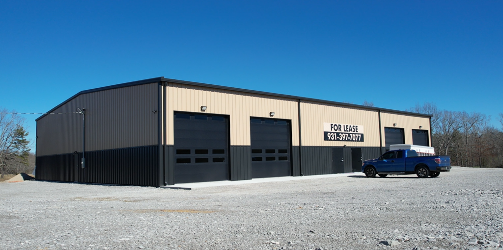 Completed NUCOR metal building with two-tone tan and black exterior and overhead doors in Crossville, TN