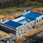 Three quarter aerial of the TCAT Livingston structural steel building with metal roof decking across both end sections and scaffolding along the center bay